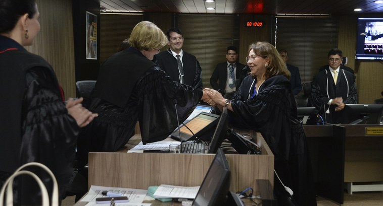 TRE-PB desembargadora Agamenilde Dias toma posse Duas mulheres se cumprimentam com aperto de mãos, enquanto outras pessoas assistem o ato, todos ...