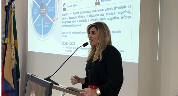 Foto interna: #PraTodosVerem: Na fotografia aparece uma mulher palestrando para o público, ao fu...