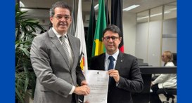 #PraTodosVerem: Na fotografia, dois homens em pé em uma sala com bandeiras ao fundo. Eles estão ...