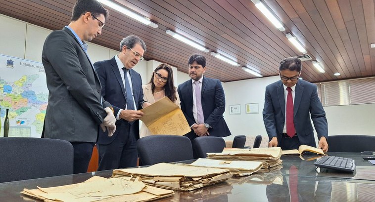 #PraTodosVerem: Na fotografia aparece cinco pessoas analisando documentos históricos dispostos e...