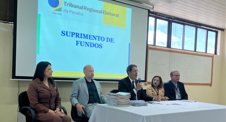 TRE-PB entrega cartões corporativos para suprimento de fundos #PraTodosVerem: Na fotografia aparecem cinco pessoas, sentadas em cadeiras, compondo uma mesa de...