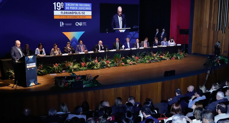 #PraTodosVerem: Na fotografia aparece um auditório em um evento formal, onde um homem de terno e...