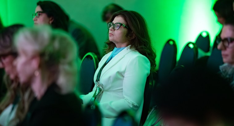#PraTodosVerem: Na fotografia aparece uma mulher, em um auditório, participando de um evento.