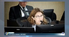 #ParaTodosVerem: Painel retangular fotografia em plano médio de uma mulher sentada por trás de u...