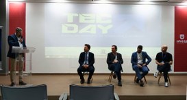 #PraTodosVerem: Na fotografia aparece o palco de um auditório, onde quatro homens estão sentados...