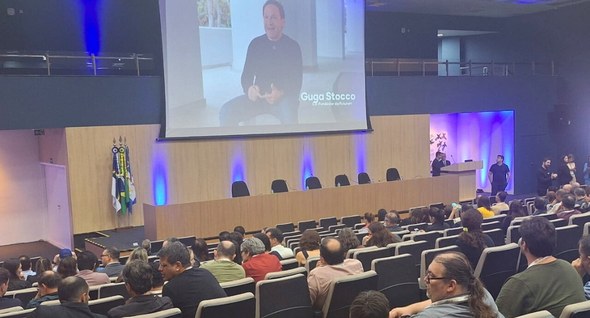 TRE-PB participou do Enastic da Justiça Eleitoral #PraTodosVerem: Na fotografia aparece um auditório com uma tela de projeção ao centro.