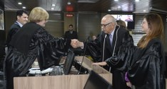 Pessoas de pé, quando duas delas se cumprimentam com aperto de mãos.