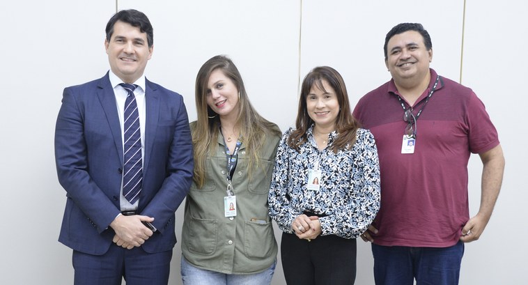 #ParaTodosVerem: Painel retangular com quatro pessoas de pé em plano médio longo, sendo dois hom...