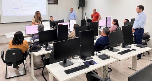 #PraTodosVerem: Na fotografia, um grupo de pessoas está reunido em uma sala de treinamento, sorr...