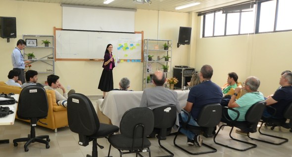#PraTodosVerem: Na fotografia aparece um grupo de pessoas, reunidas em uma sala, sendo que um ho...