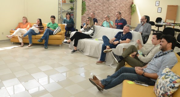 #PraTodosVerem: Na fotografia aparece um grupo de pessoas, reunidas em uma sala, sentados em sof...