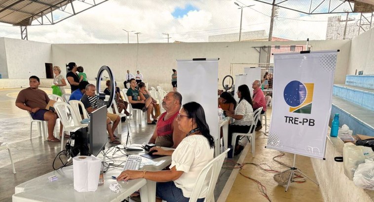 #PraTodosVerem: Na fotografia aparece uma servidora do TRE-PB atendendo um cidadão, sentada em u...