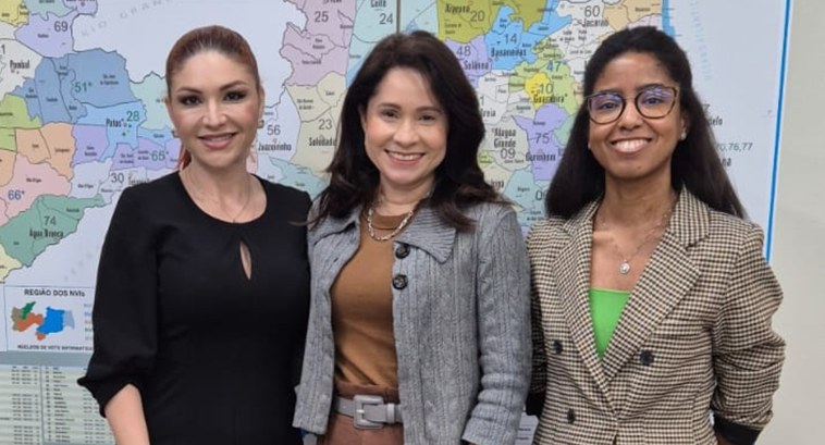 TRE-PB realiza reunião para definir cronograma de Círculos de Construção de Paz #PraTodosVerem: Na fotografia aparecem três mulheres posando; atrás delas aparece um mapa da Par...