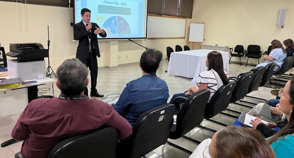 Foto 2: #PraTodosVerem: Na fotografia aparece um homem de terno escuro em pé, à frente, ministra...