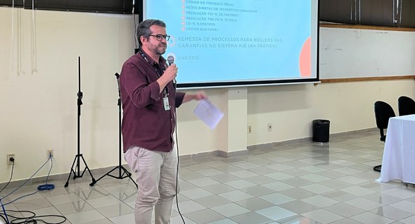 Foto 6: #PraTodosVerem: Na fotografia aparece um homem em pé, usando uma camisa vinho, de frente...