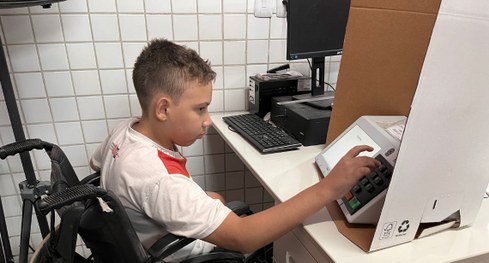 #PraTodosVerem: Na fotografia aparece uma criança com deficiência física votando na urna eletrôn...