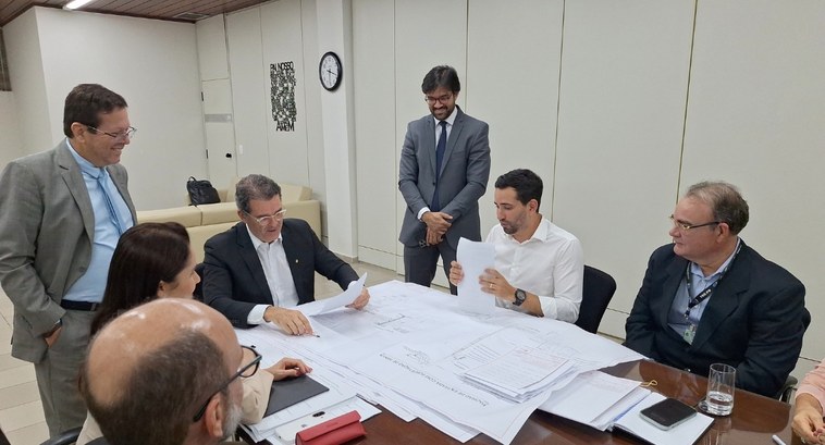 TRE-PB recebe projeto de implantação de Usina Fotovoltaica #PraTodosVerem: Na fotografia aparecem várias pessoas em torno de uma mesa avaliando papéis e pr...