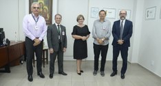 #ParaTodosVerem: Cinco pessoas de pé posam para fotografia, a do centro é uma mulher.