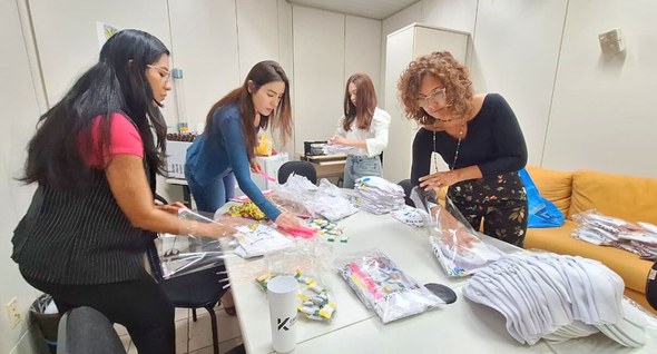 TRE-PB se prepara para a realização da 5ª edição dos Jogos Internos #PraTodosVerem: Na fotografia aparece, quatro mulheres preparando kits do sjogos numa mesa de tr...