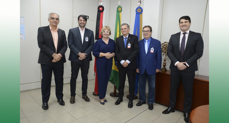 TRE-PB visita institucional da PMJP #ParaTodosVerem: Painel retangular com seis pessoas de pé, posando para fotografia, uma delas é ...