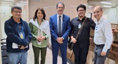 #PraTodosVerem: Cinco pessoas em pé, sendo quatro homens e uma mulher, posando em um corredor do...