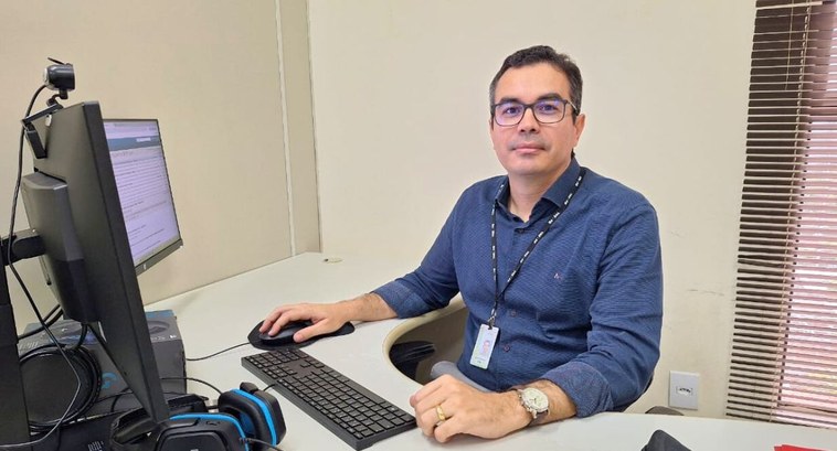 TRE-PB_Tribunal reconduz para segundo mandato secretário de auditoria interna #PraTodosVerem: Na fotografia aparece um homem sentado tendo computadores à frente