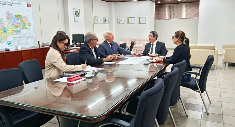 #PraTodosVerem: Na fotografia aparecem pessoas reunidas em torno de uma mesa de reunião, tendo o...