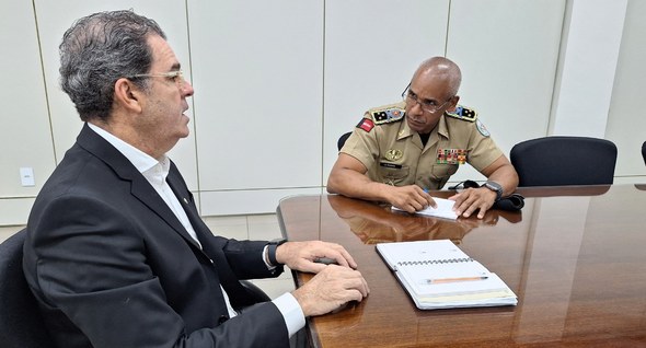 #PraTodosVerem: Na fotografia aparecem dois homens, sentados em cadeiras, reunidos em volta de u...