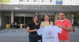 #PraTodosVerem: Na fotografia aparece um grupo de três pessoas, sendo duas mulheres e um homem, ...