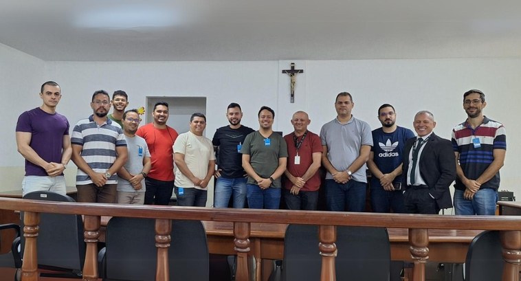 Voluntários que atuarão como ALVTs são capacitados na 8ª Zona Eleitoral #PraTodosVerem: Na fotografia aparecem treze homens, posando; em primeiro plano aparece um balcã...