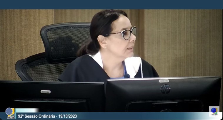 Foto juíza Maria Cristina Paiva Santiago #ParaTodosVerem: Mulher sentada a frente de dois monitores de computador, na Sessão Ordinária do...